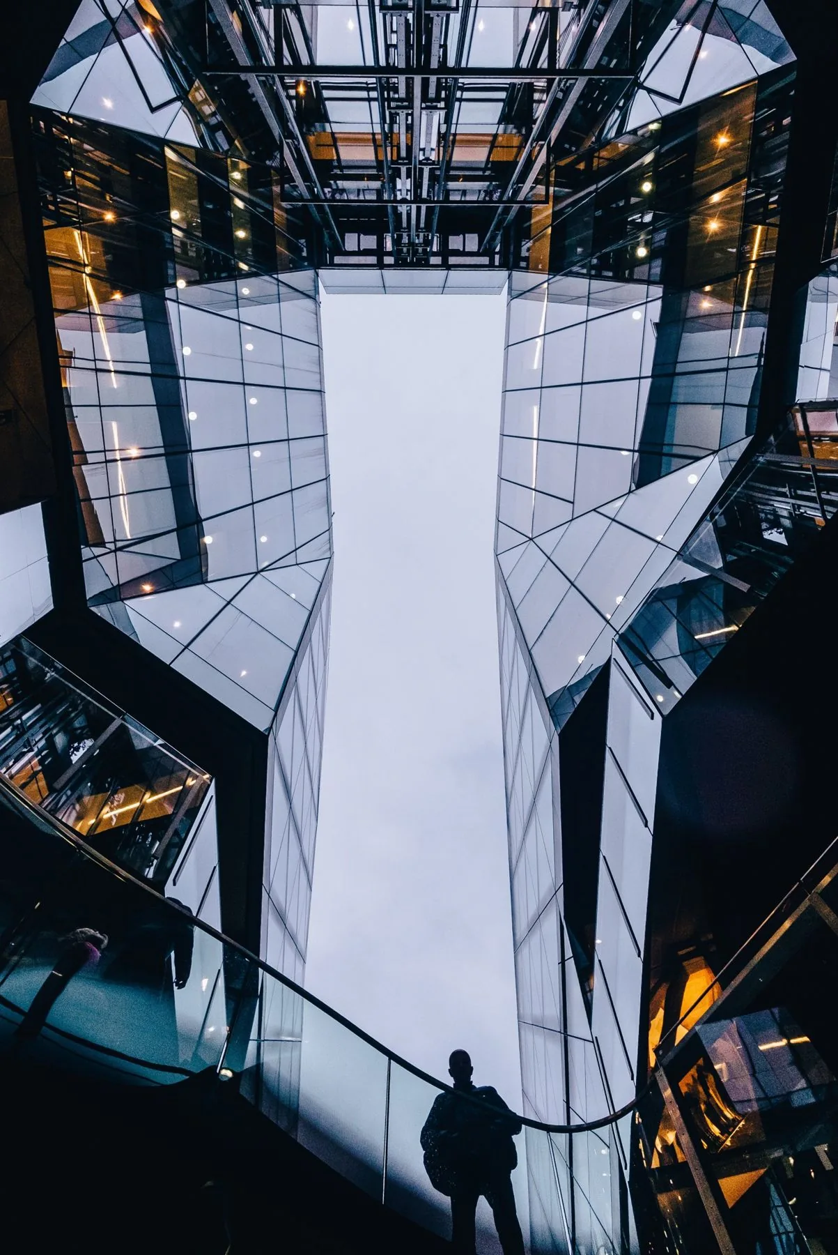 Looking up through a glass atrium with lift shafts