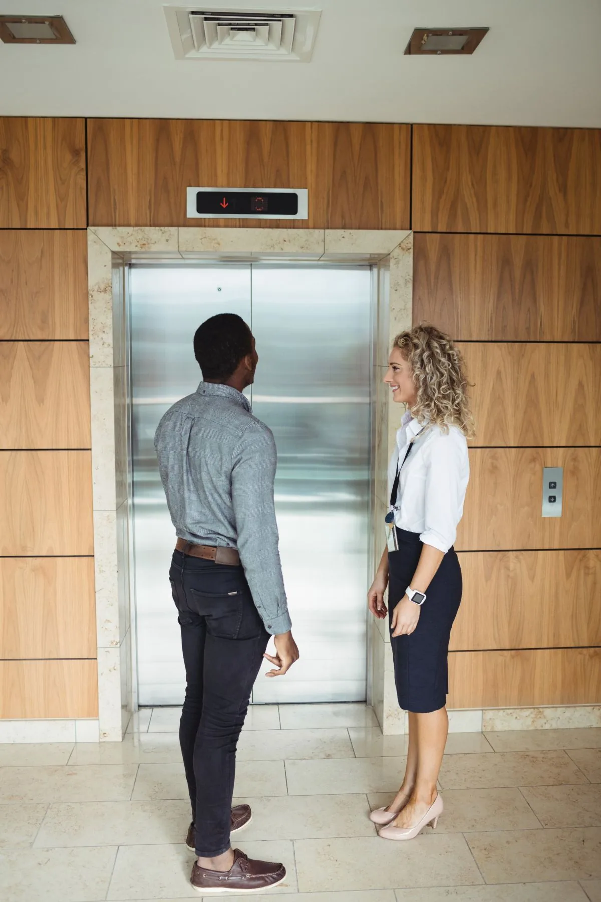 Stainless steel lift doors in a timber-panelled office lobby
