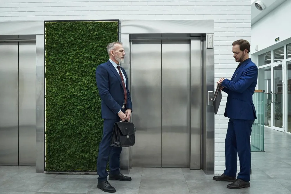 Building managers discussing a lift upgrade beside stainless steel lift doors
